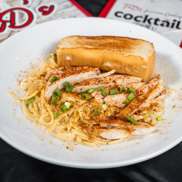Tad's Louisiana Cooking chicken pasta with toasted bread, green onions, and seasoning.