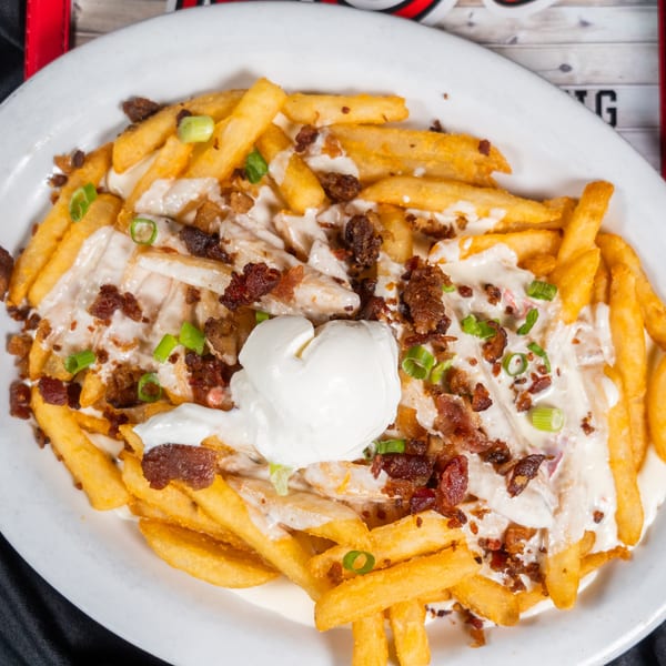 Loaded french fries topped with melted cheese, bacon bits, green onions, and a dollop of sour cream.