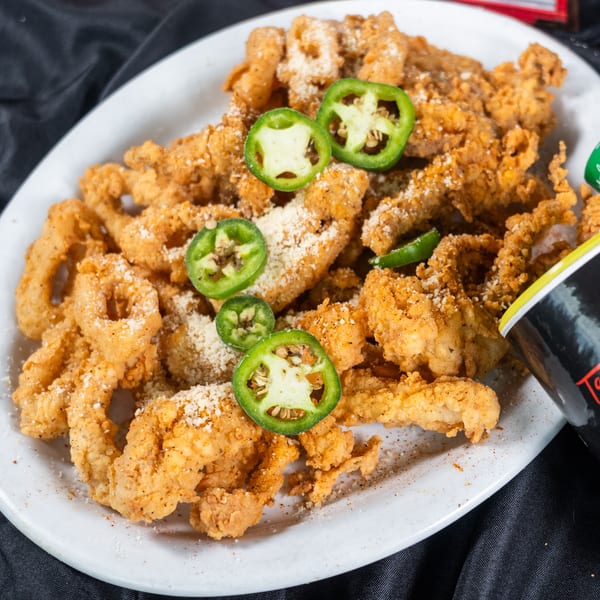 Fried calamari and shrimp with jalapeños and parmesan cheese, next to a bottle of Tad's Louisiana seasoning.